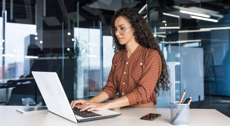 A person working on a laptop in a modern office environment.