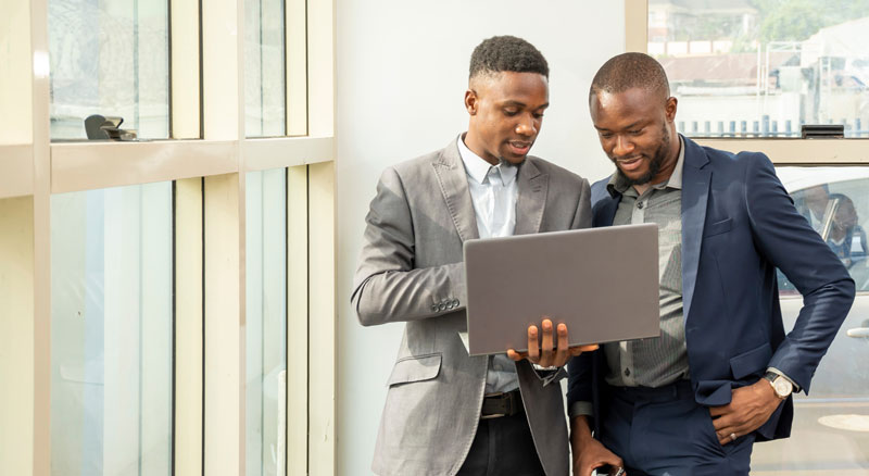 Two professionals examining a laptop together near a window