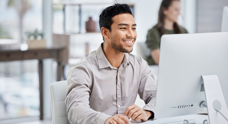 Smiling man uses desktop computer