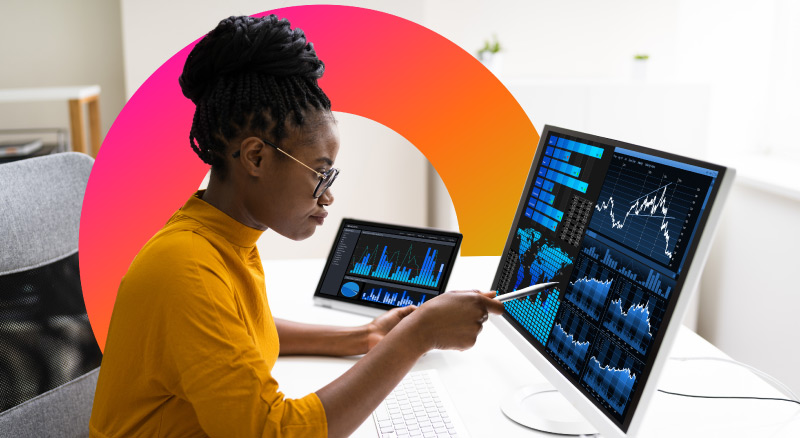 A person analyzing financial data on multiple screens with colorful graphs and charts, while pointing at one of the screens with a stylus