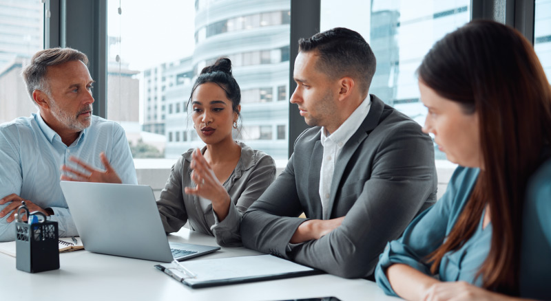 Four professionals having a discussion around a table in an office setting