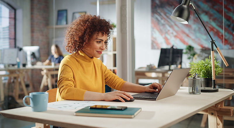 An individual sitting at a desk, focused on their laptop, working diligently.