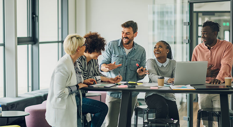 A group of people attentively listening to one person speaking at a table.