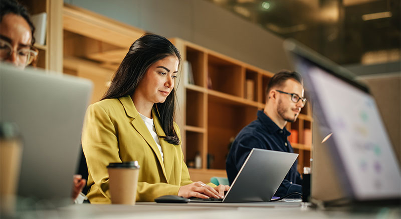 An individual  focused on a laptop in a modern, well-lit office environment