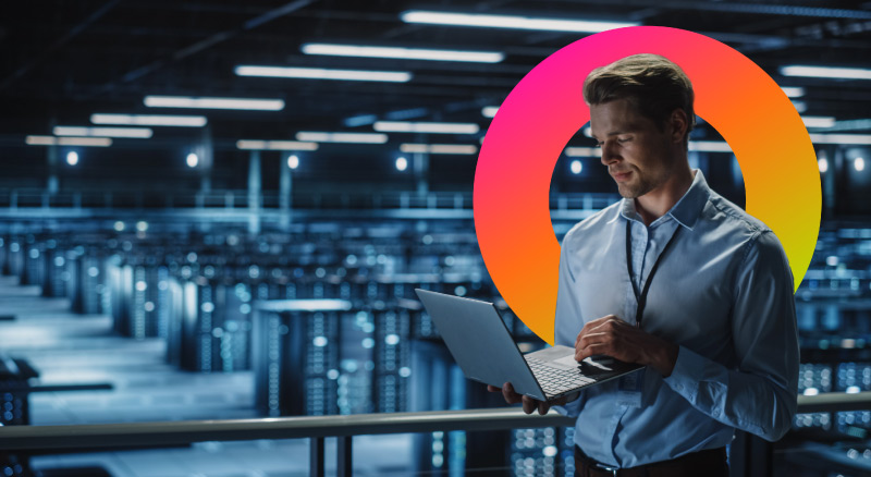 A person holding a laptop in a large data center