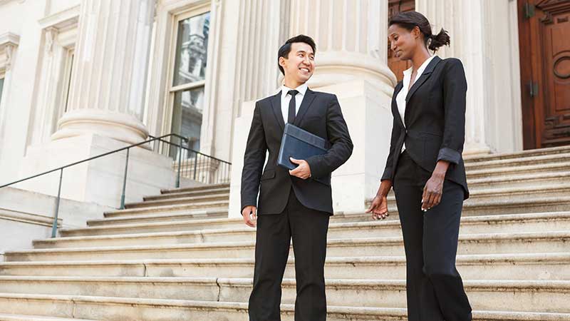 Man and woman in business attire walking down building stairs