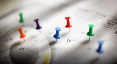Push pins sticking into different dates on a calendar