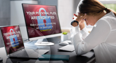 A distressed person looking at a ransomware message on their computer and tablet