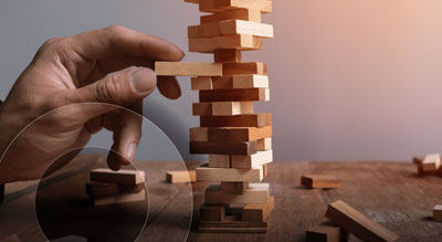 A hand carefully removes a piece from a stack of wooden blocks