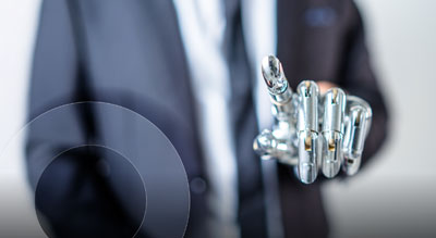 A person wearing a business suit points forward revealing a robotic hand