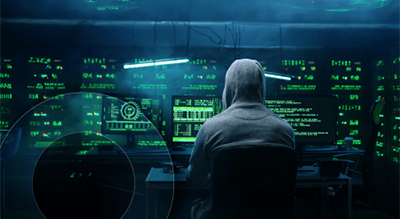 A person wearing a hoodie sits at a computer, focused on the screen in a casual indoor setting