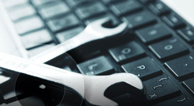 A silver wrench lying diagonally across a black computer keyboard, suggesting a concept of computer repair or maintenance