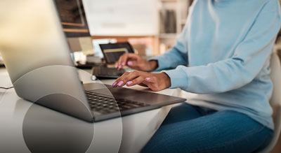 An individual typing on both a laptop and a desktop keyboard