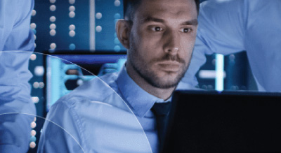 A person in office attire working on a computer in a blue-lit room