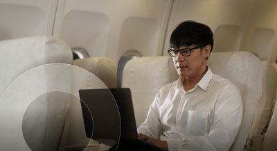 A person is sitting in an airplane seat using a laptop