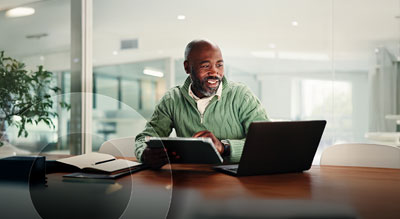 An employee using a tablet and laptop in a modern office