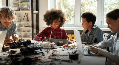 Children collaborating on a laptop while constructing a Lego project on a table