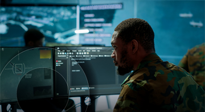 A soldier intently gazes at a computer screen, focused on the task at hand