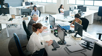 An office filled with employees busy at work behind computer monitors