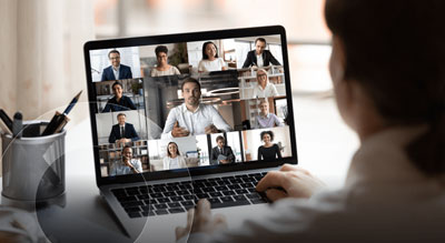 An individual participating in a video conference on a laptop
