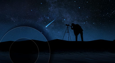 A wide shot of a person looking through a telescope at the night sky