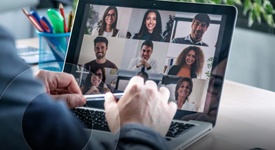 A person is engaged in a virtual meeting with several participants on their laptop, showcasing the modern approach to professional communication and collaboration