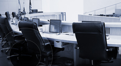 An empty government conference desk with multiple computer monitors and chairs
