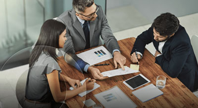Three individuals engrossed in conversation during a business meeting held over a table