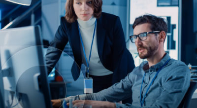 Two people working over a computer