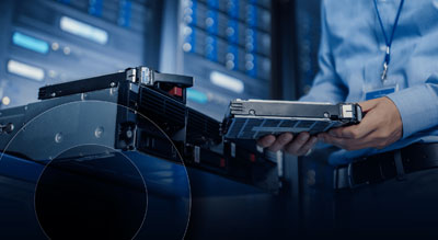The image depicts a technician handling a server blade within a data center