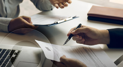 A close up of a desk with employees hands, documents and a laptop