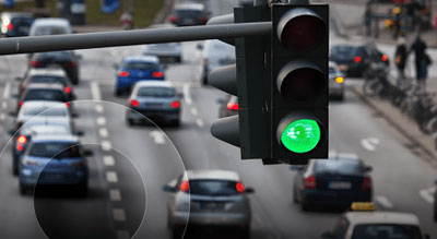 A traffic light with a green signal against a backdrop of a busy street with multiple lanes of traffic