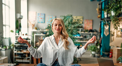 An employee sitting with hands up in meditation pose