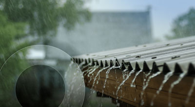 Rainwater dripping from the edge of a corrugated metal roof during a refreshing shower