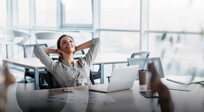 An employee in a modern office leaning back with their hands behind their head