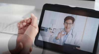 A person holds a tablet displaying a video of a doctor, illustrating a virtual consultation or medical advice session