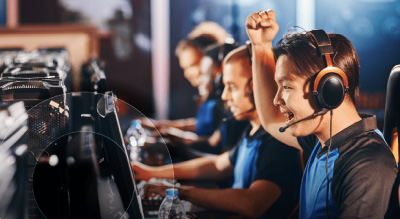 Several individuals in a gaming room, focused on screens and interacting with each other in a lively atmosphere