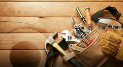 A tool belt filled with various hand tools on a wooden surface