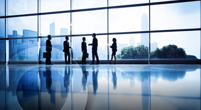 A wide photo of employees in a corporate office with large windows
