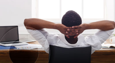 A person relaxing in an office chair with their hands supporting their head