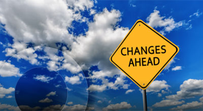 A yellow diamond-shaped road sign with the text 'CHANGES AHEAD' against a backdrop of a bright blue sky with fluffy white clouds