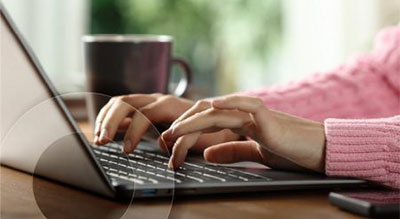 A close up of an employee working on a laptop at a desk