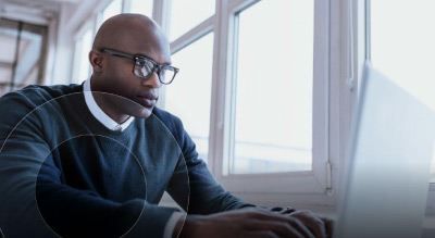 A person with a working on a laptop in front of a window