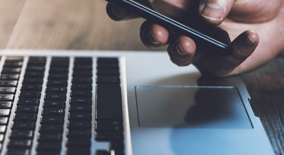 Hand operating smartphone and laptop