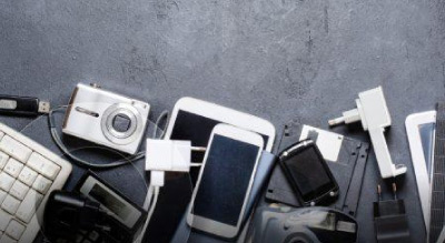 A collection of various electronic devices, including a camera, smartphones, and keyboards, scattered on a dark surface