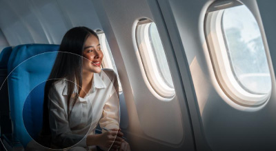A person sitting by the airplane window. The individual appears to be looking outside the window while seated in a blue airplane seat, capturing a moment of travel.