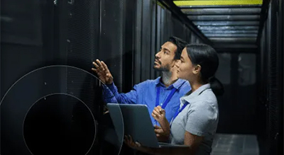 Two individuals examining a server within a modern data center environment