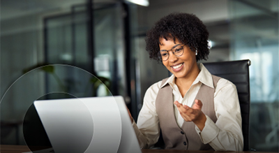 A person smiling at computer screen in office setting.