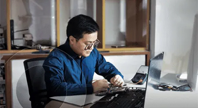 A man focused on his laptop, seated at a desk, engaged in work with a professional demeanor