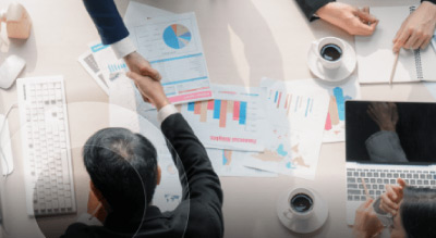 A group of people working on a project with charts and graphs at a large table, viewed from above